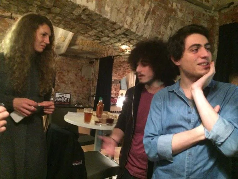 Three people talking in the brick cellar, one laughing with his chin in his hand