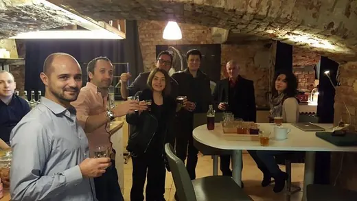 A group raising glasses round a table under a pendant lamp