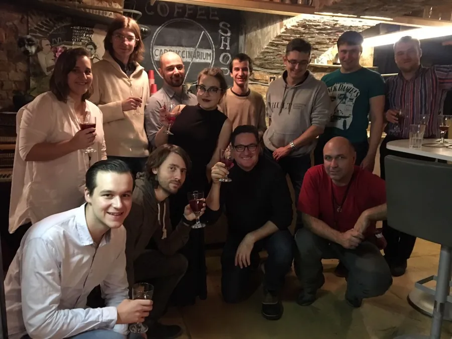 A group photograph, some crouching at the front, glasses raised