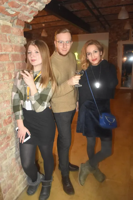 Three people posing against the brick wall