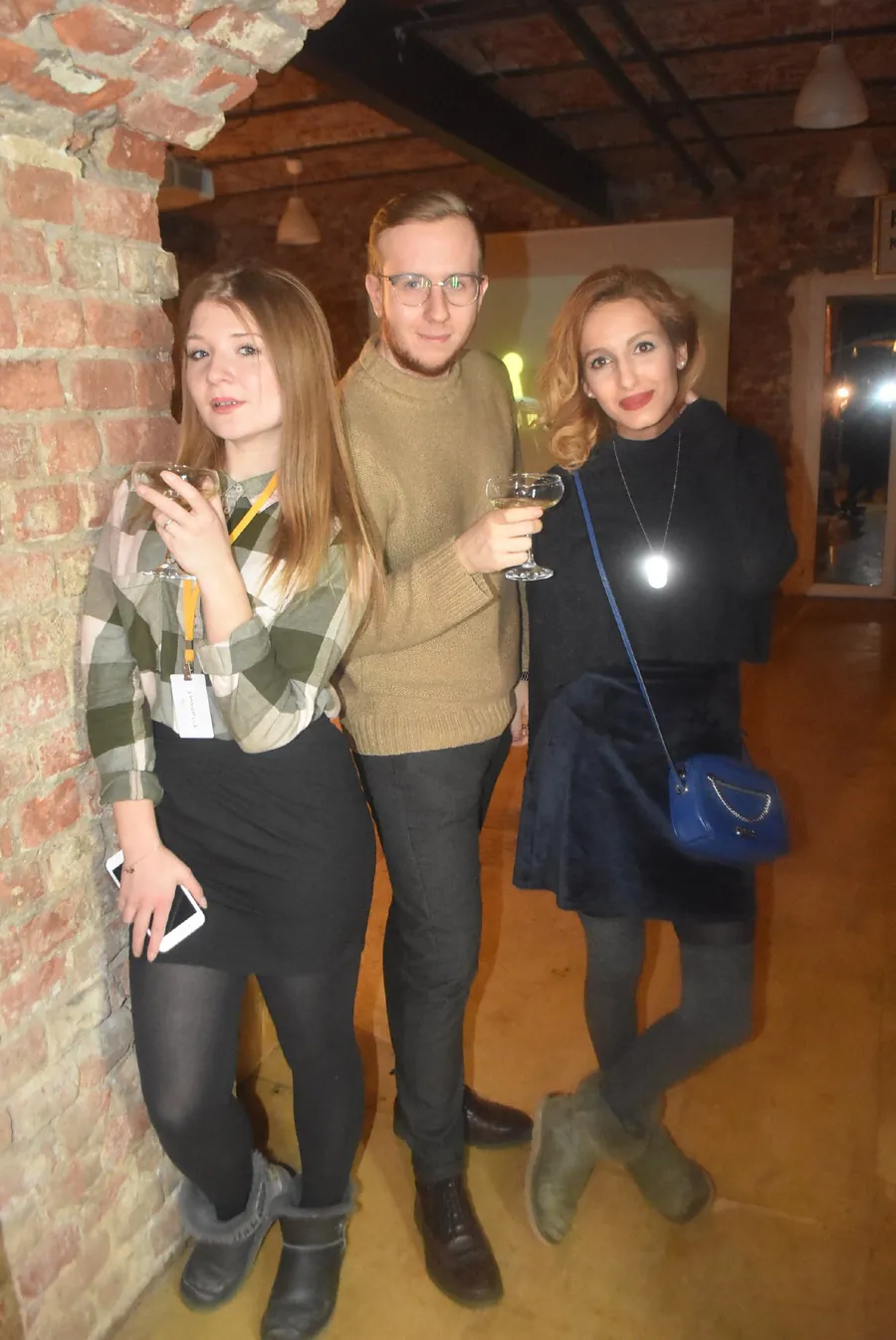 Three people posing against the brick wall