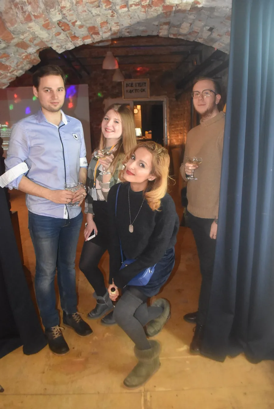 A small group posing beside a curtain