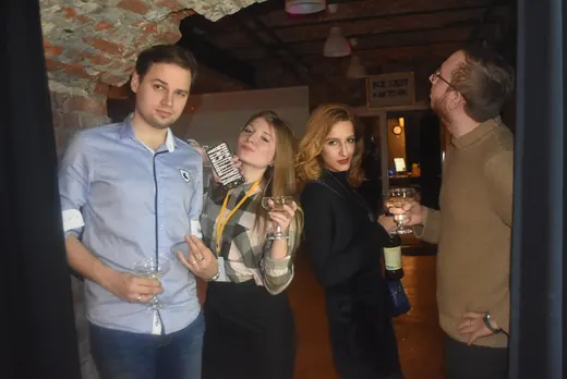 Four people with drinks beside a curtain