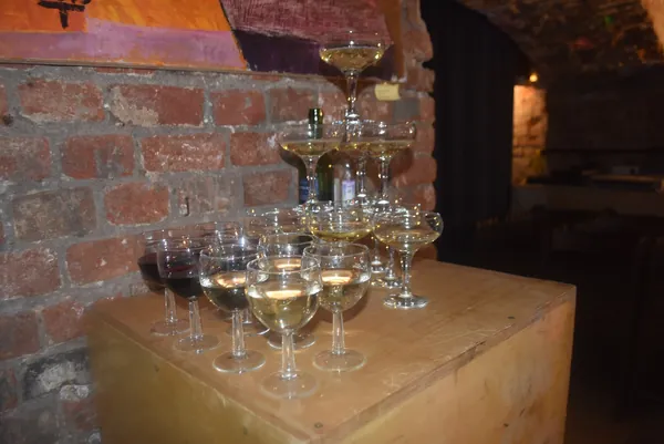 A tower of stacked coupe glasses on a wooden crate against a brick wall