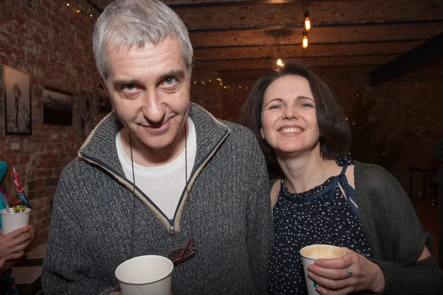 Two guests smiling at the camera with cups in hand