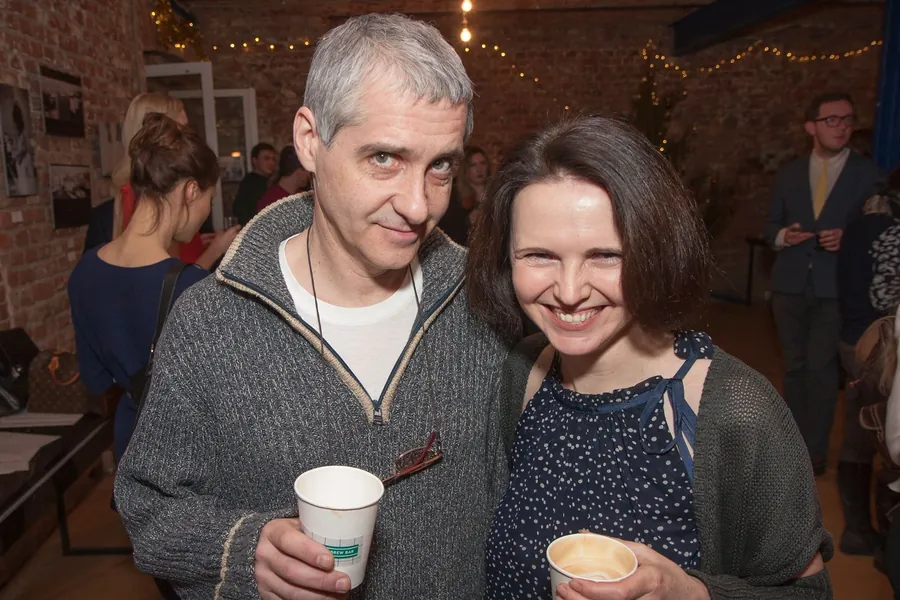A man and a woman laughing together, cups in hand