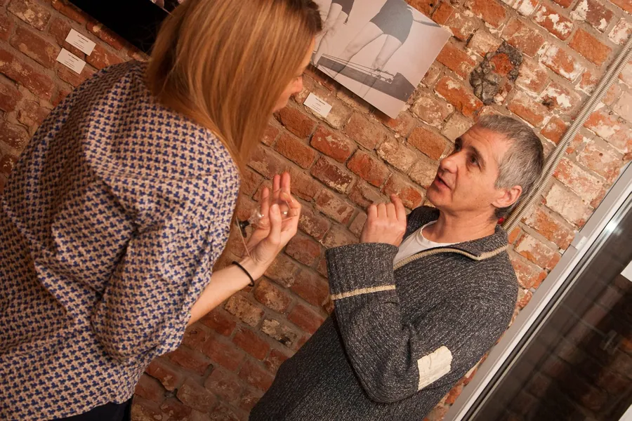 Two men talking closely against the brick wall