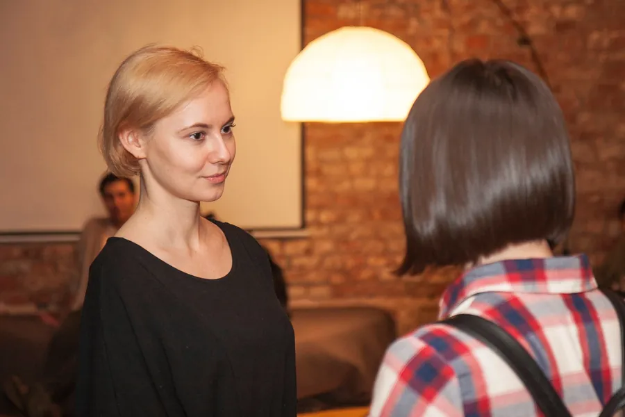 Two women talking under a pendant lamp