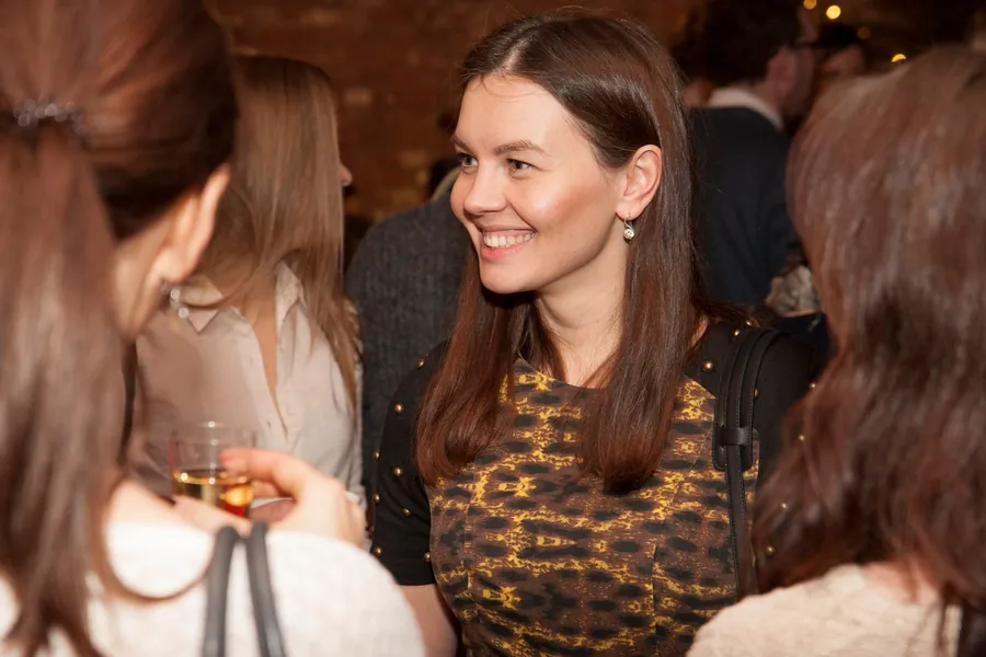 A woman laughing mid-conversation, a glass in her hand