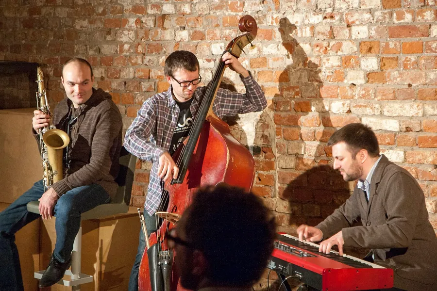 A jazz trio - saxophone, double bass and piano - in the brick room