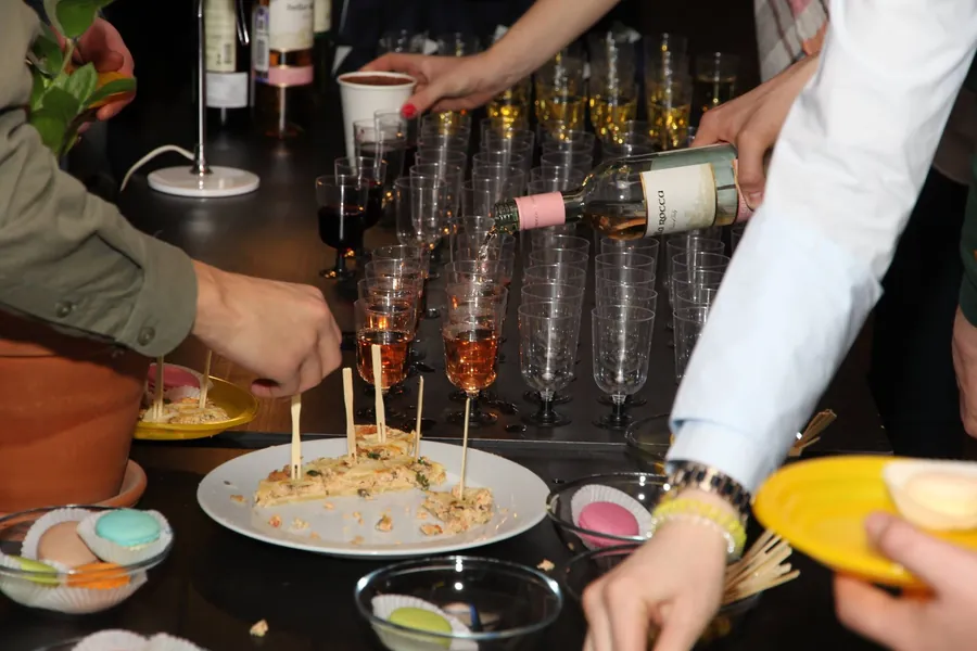 Champagne being poured into a row of flutes, canapés on a plate below