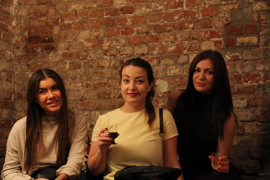 Three women on a bench, one with a glass of red