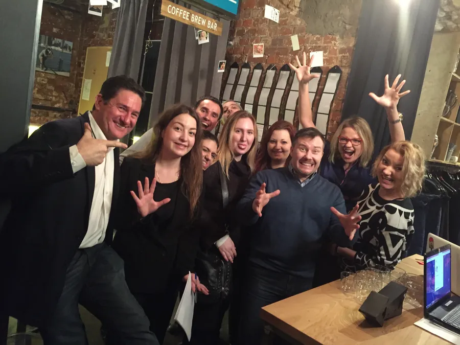 A group posing by the bar, arms out, grinning