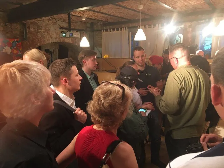 People mingling under the lamps, a man in red