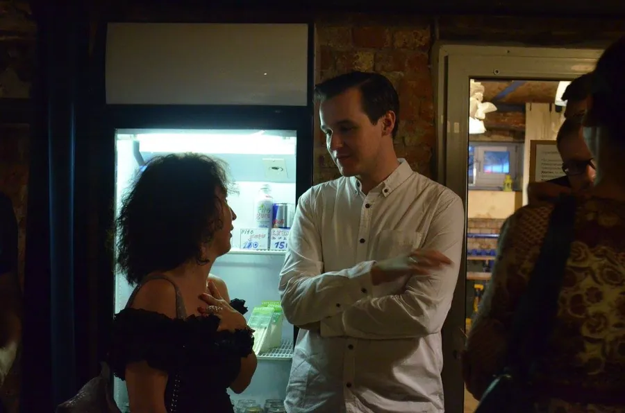 A man in a white shirt and a woman with curls by the fridge