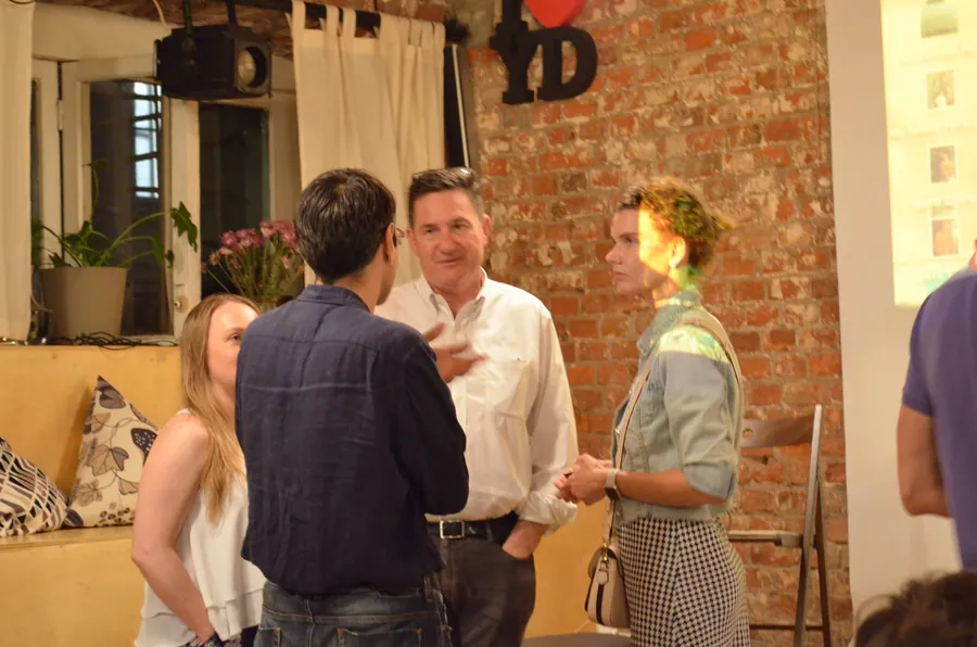 A man in a blue jacket talking to two women