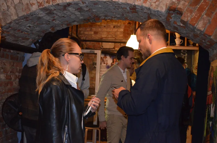 A woman in a leather jacket talking with two men