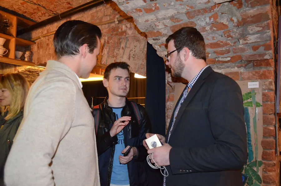 Three men, one showing the others something on his phone
