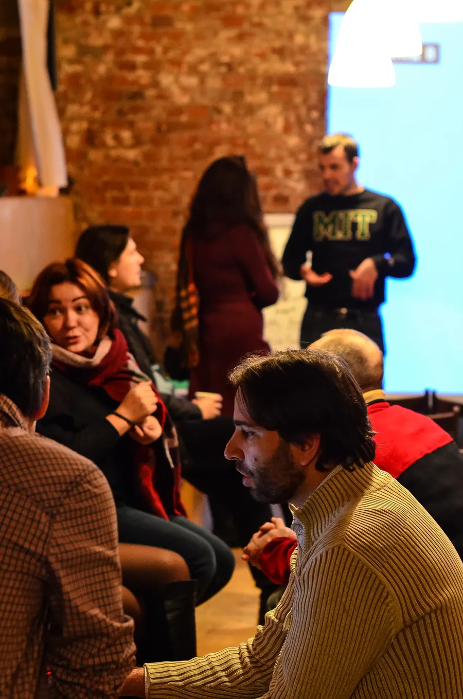 A man in an MIT sweatshirt talking to a woman in a burgundy scarf