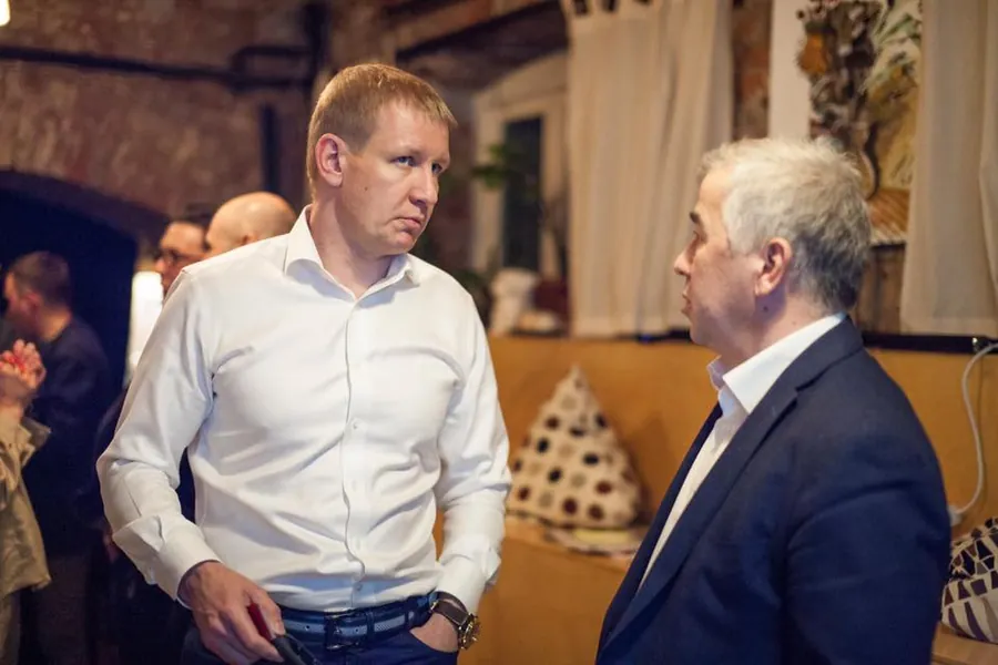 Two men talking, one in a white shirt with his hands in his pockets
