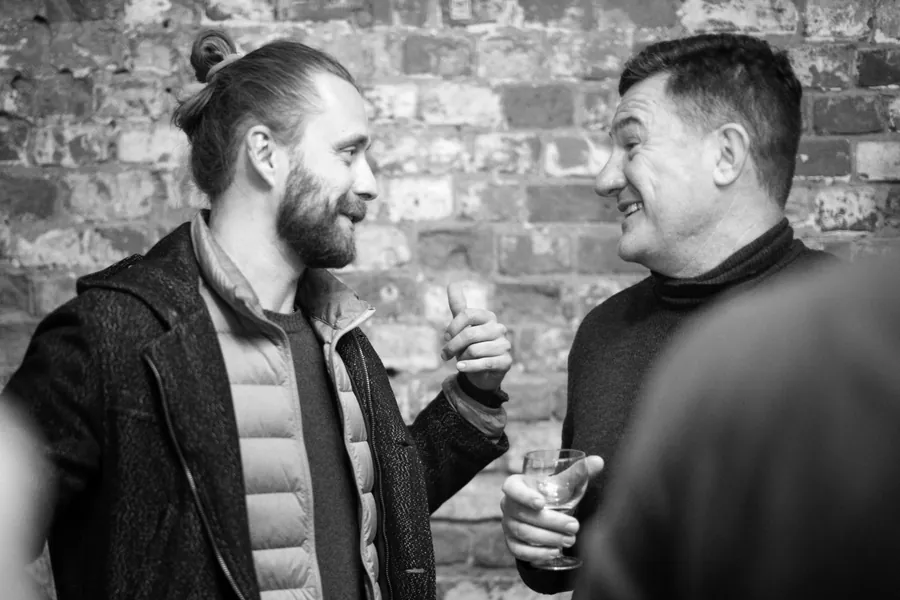Two men deep in conversation against the brick, in black and white