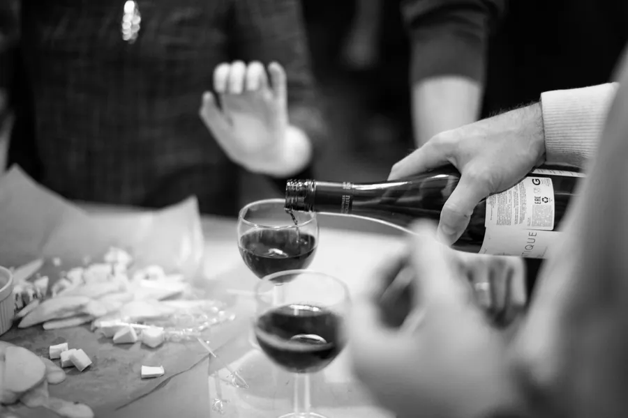 Wine being poured over a table of food, in black and white