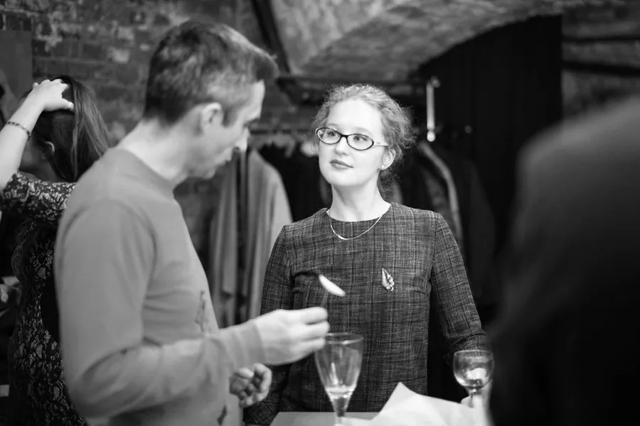 A man and a woman in glasses talking, black and white