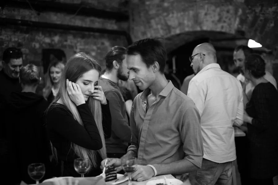 A woman with a hand to her ear, a man in a white shirt beside her, black and white