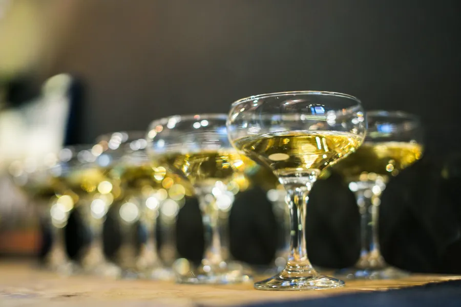 A tower of coupe glasses filled with champagne, close up