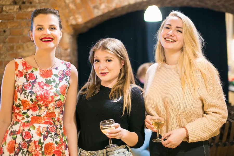 Three young women with coupes of champagne, smiling
