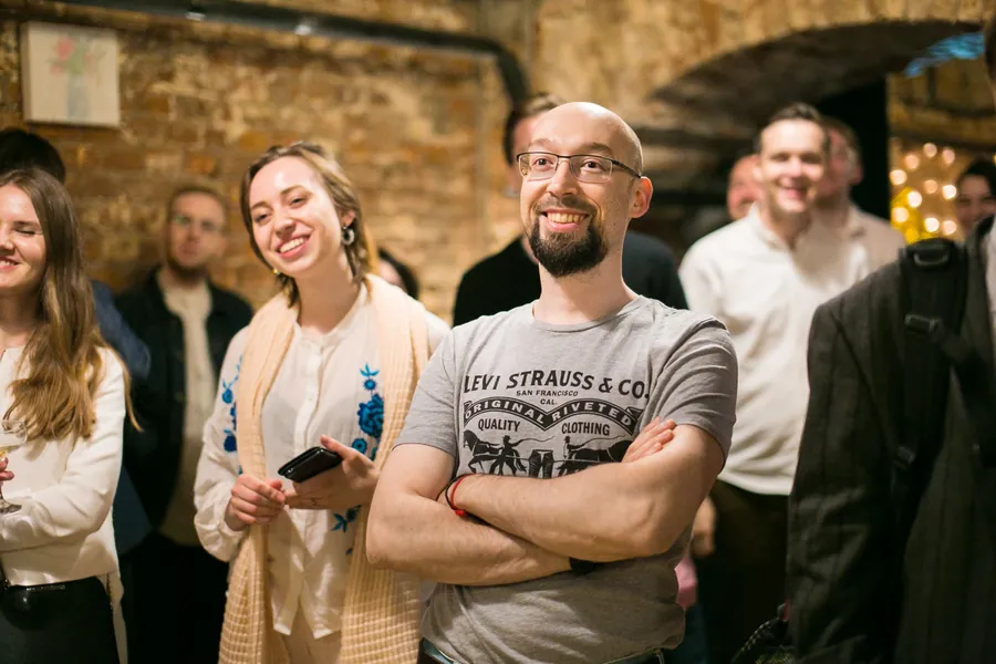 Guests in a row along the brick wall, glasses in hand, smiling