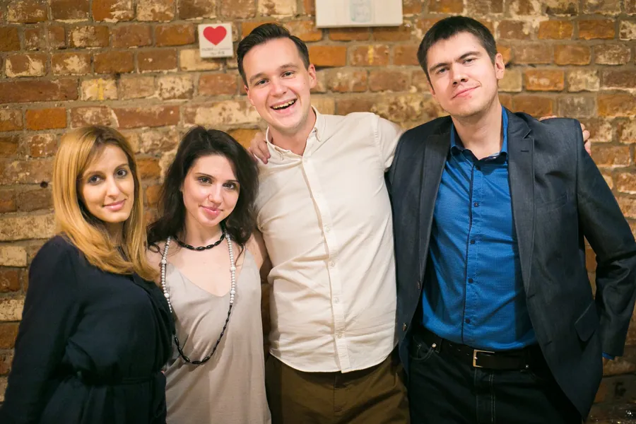 Four guests arm in arm in front of the brick wall