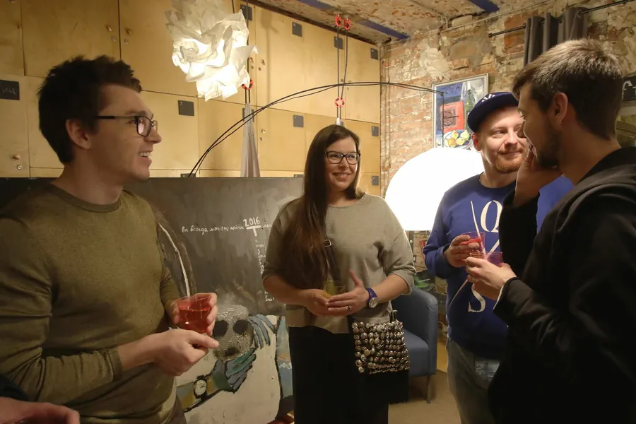 Two men and a woman with a drawing, one in a cap