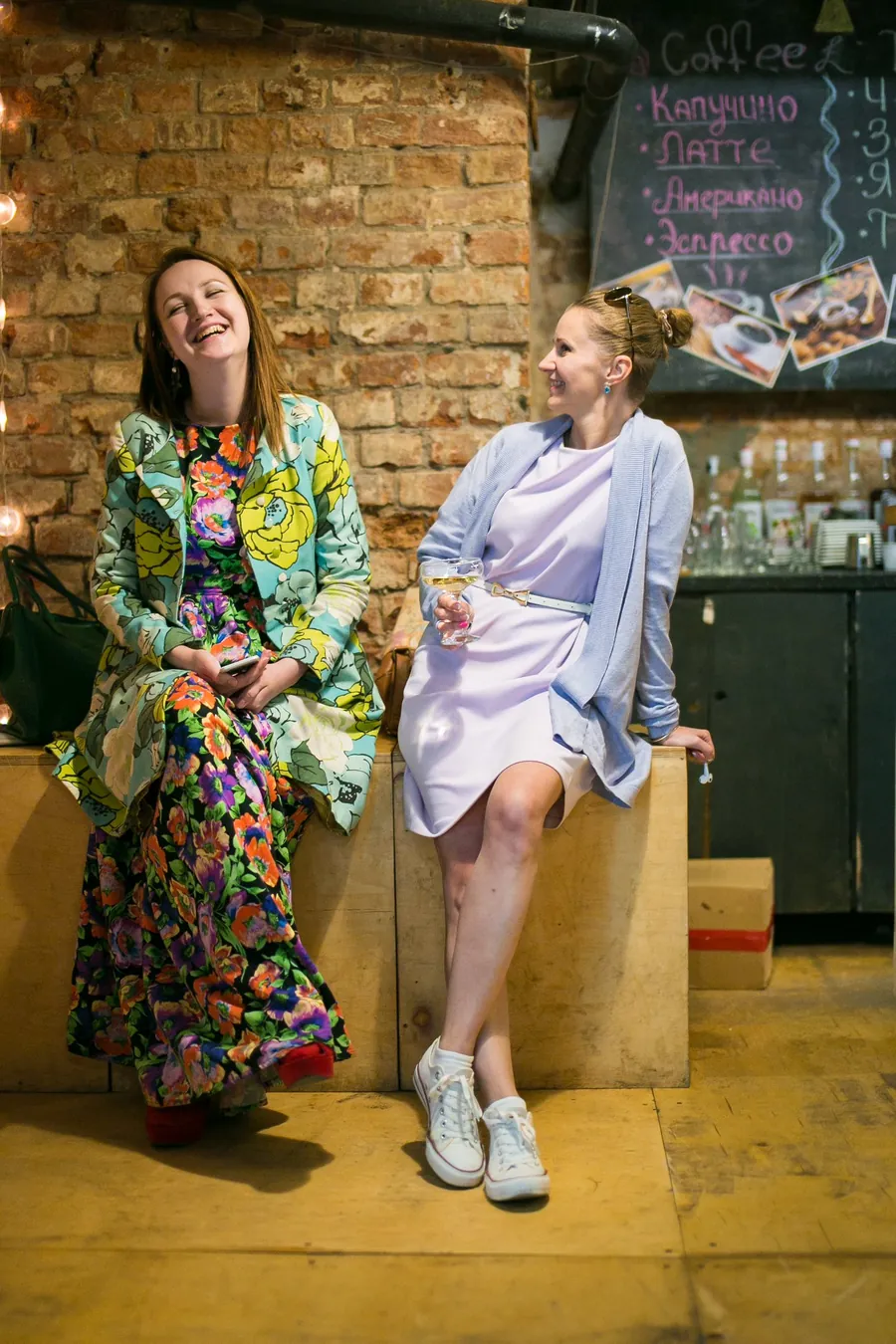 Two women perched on the boxes, one in a flowered coat