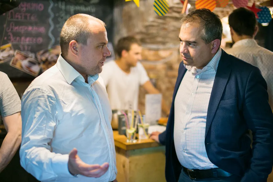 Three men talking by the bar, one gesturing