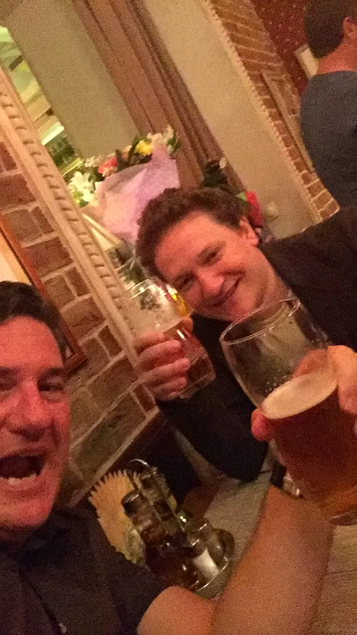 A man grinning over two glasses of beer