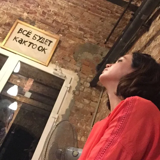 A woman in red laughing, head thrown back