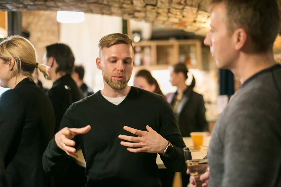 A man in a black jumper explaining with both hands