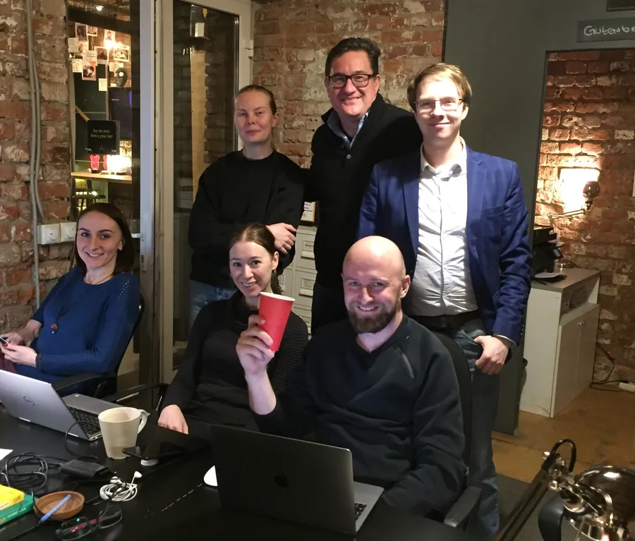 A group posing round a laptop, one with a red cup