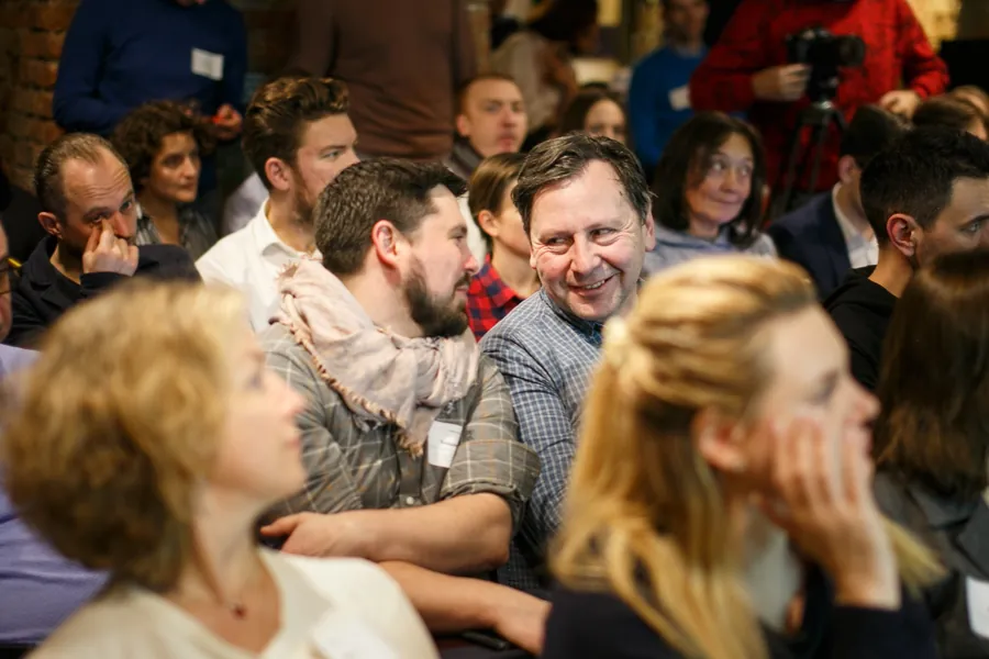 An audience laughing, a man in a blue shirt turning round